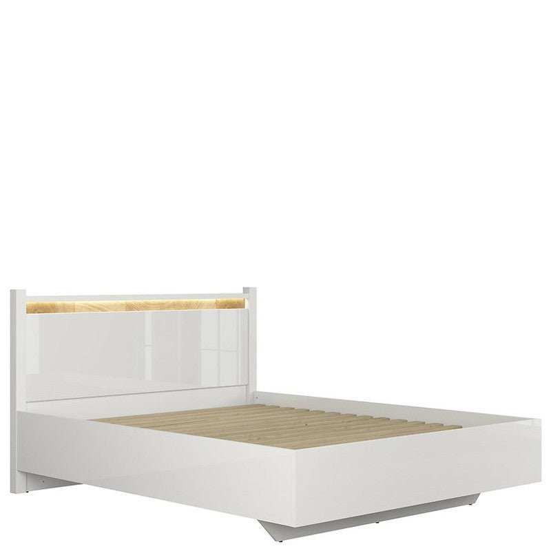 Modern king size bed with trapezoidal base, white gloss finish, LED headboard lighting, and wooden slats.